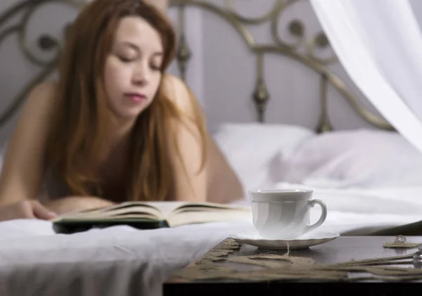 Jovem bela mulher sexy leitura livro em uma cama no quarto de hotel — Fotografia de Stock