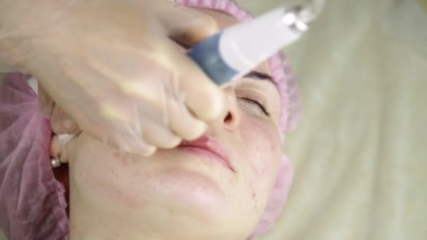 Kosmetikerin putzt Gesicht mit Kosmetikgeräten, um Mädchen zu picken — Stockvideo