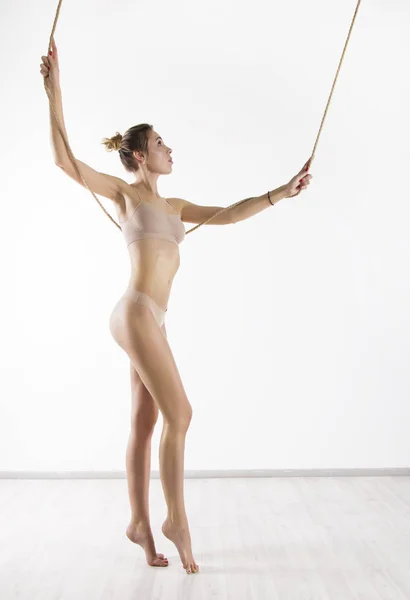Perfecte vrouw in beige lingerie met prachtige sexy figuur poseren met touw op witte achtergrond — Stockfoto