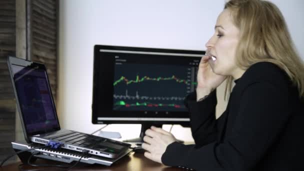 Ženské obchodník Mluvil po telefonu a sledovat graf výměny měny na monitor počítače. Práce na šifrovací burze — Stock video