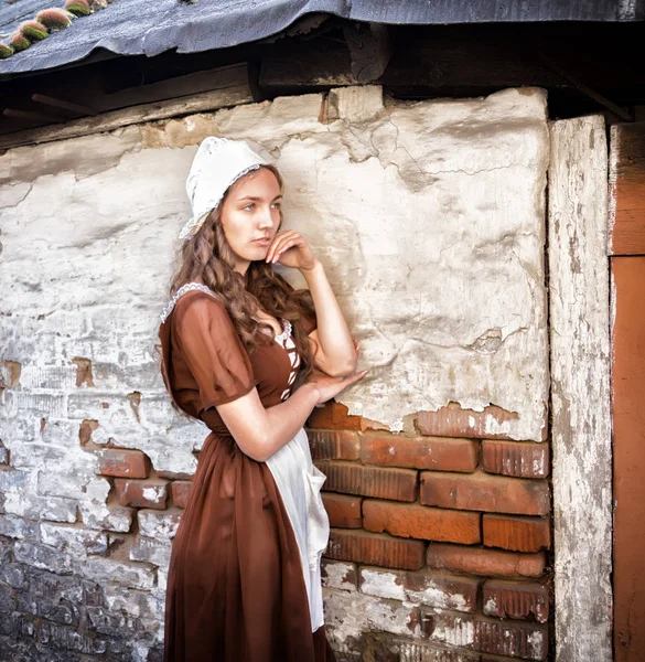 Pensive young woman in a rustic dress standing near old brick wall in old house feel lonely. Cinderella style — Stock Photo, Image