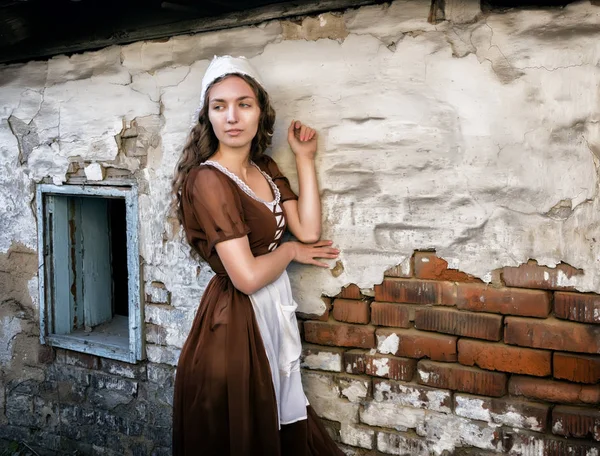 Nadenkend jonge vrouw in een rustieke jurk staande in de buurt van oude bakstenen muur in oude huis gevoel eenzaam. Cinderella stijl — Stockfoto