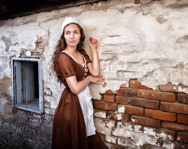 素朴なドレス立っている古い家が感じて孤独で古いれんが造りの壁の近くで物思いにふける若い女性。シンデレラ スタイル — ストック写真