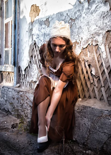 白い靴をドレスアップしようと古い家の古いれんが造りの壁に近い素朴なドレス座っている悲しい女。シンデレラ スタイル — ストック写真