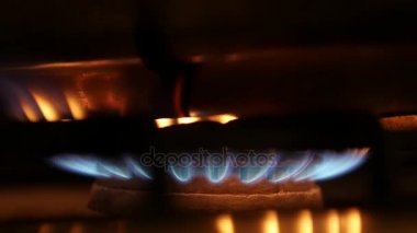 bir gaz sobası karanlıkta turuncu ve mavi alevleri