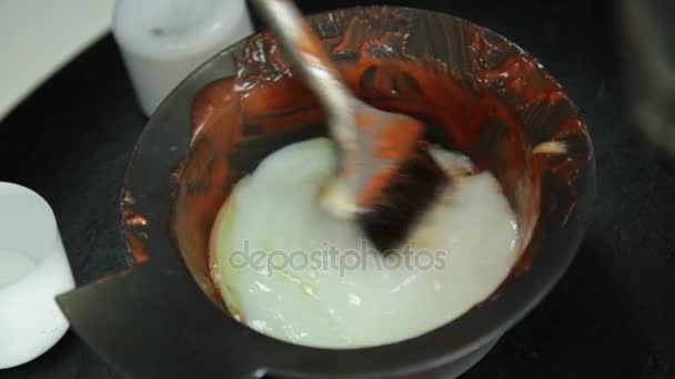 Preparación de tinte para el cabello, colorista se agita con un tinte rojo cepillo, concepto de salón de belleza — Vídeos de Stock