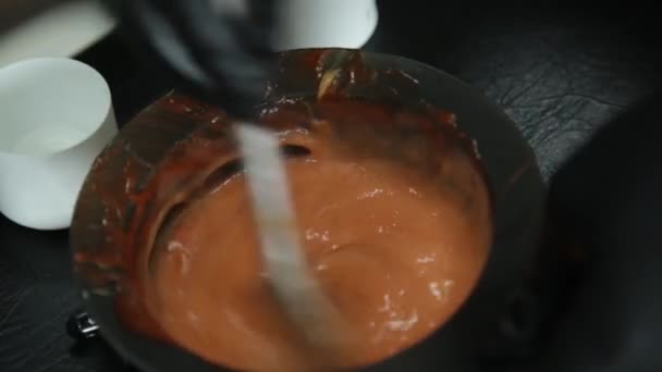 Preparación de tinte para el cabello, colorista se agita con un tinte rojo cepillo, concepto de salón de belleza — Vídeos de Stock