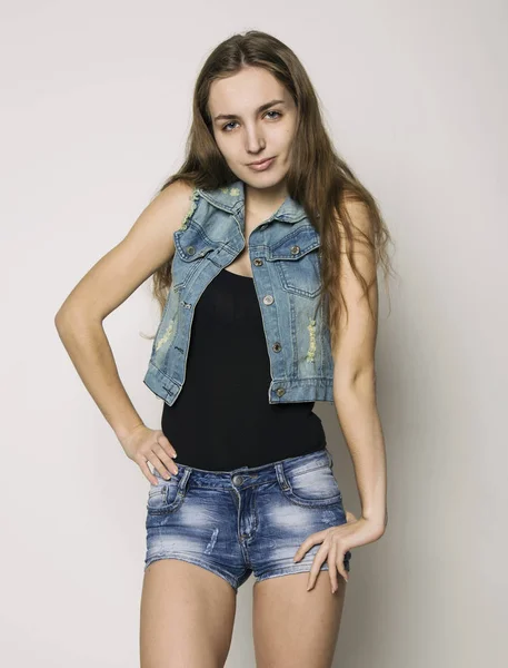 Fiatal szép boldog elegáns csípő lány farmer dzseki és nadrág, pózol a világos háttér — Stock Fotó