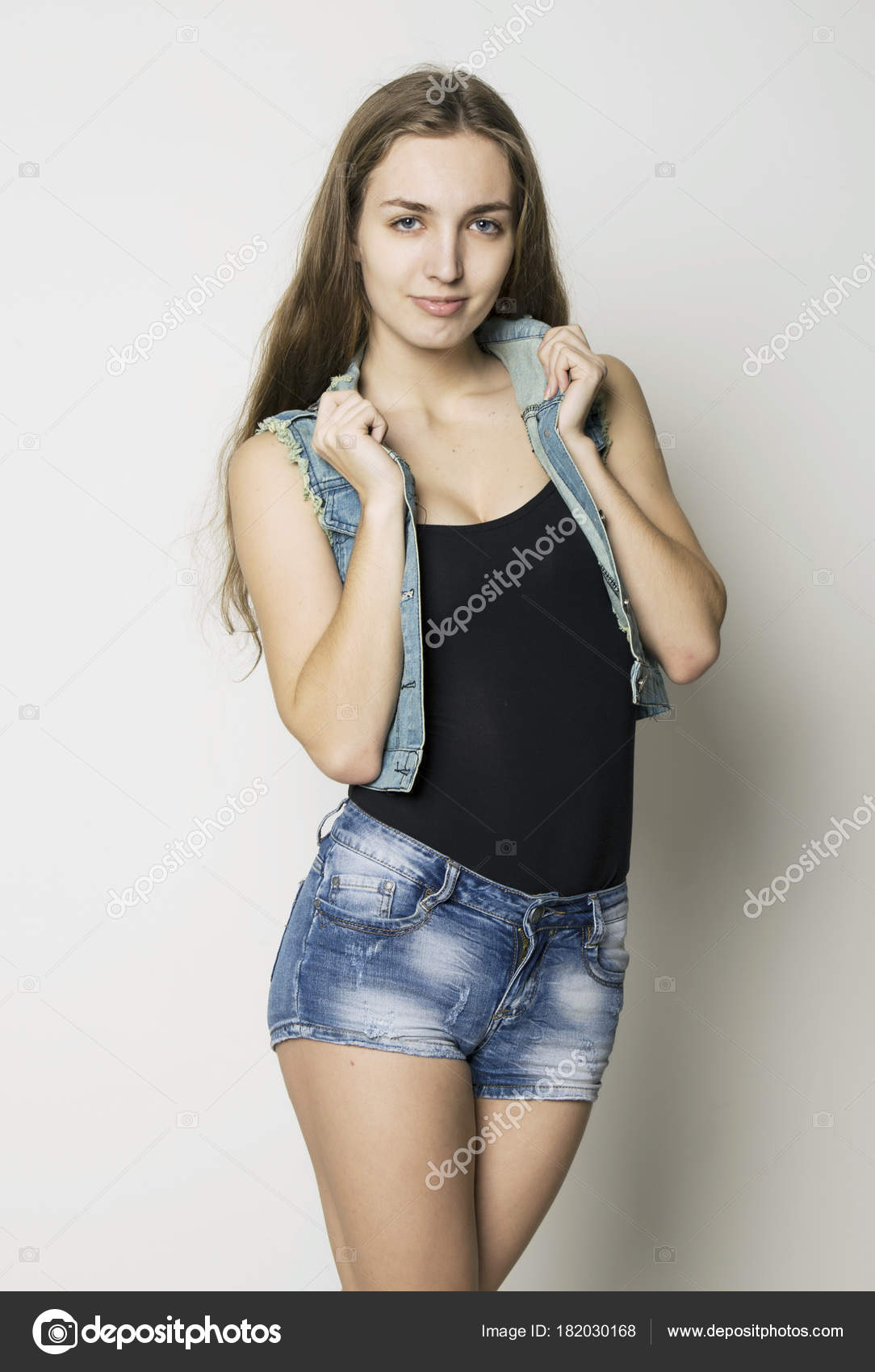 Young beautiful happy stylish hipster girl in a denim jacket and shorts ...
