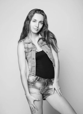 genç güzel mutlu şık hippi kız bir kot ceket ve hafif bir arka plan üzerinde poz şort. siyah ve beyaz