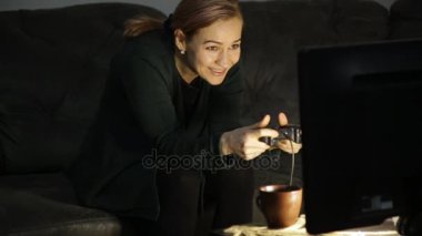 Güzel sarışın kız evde karanlıkta kanepede bir oyun konsolu ile oynarken