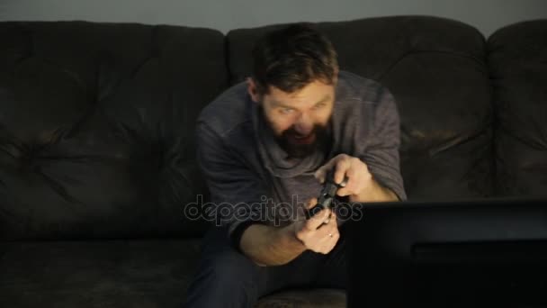 Attraktiver Kerl, der zu Hause im Dunkeln mit einer Spielkonsole auf dem Sofa spielt — Stockvideo