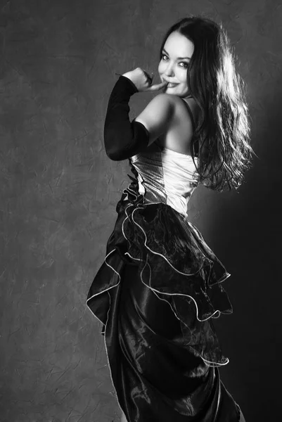 Jovem mulher em um vestido espanhol dançando em um fundo cinza. preto e branco — Fotografia de Stock