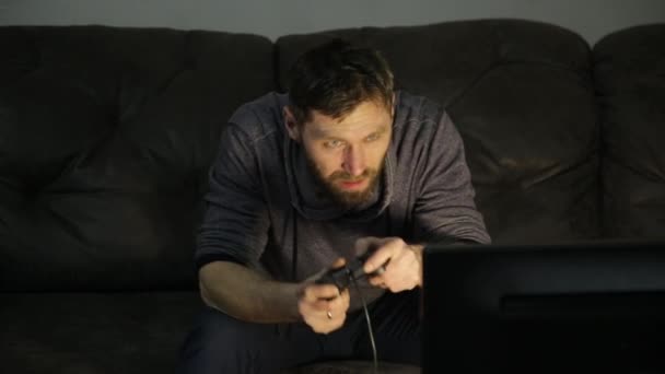 Aantrekkelijke jonge man speelt op een moderne videocontrole in donker — Stockvideo