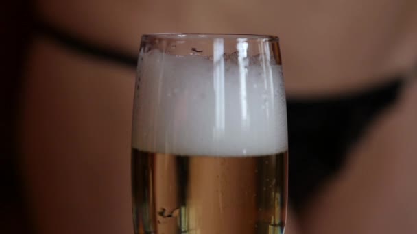 Sexy mladá žena v mini bikiny nalévá šampaňské v brýlích v temnu. Detail hýždě a kyčle — Stock video