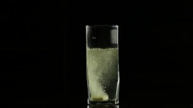 Bir bardak su koyu arka plan, yavaş hareket içinde eriterek yakın çekim Tablet