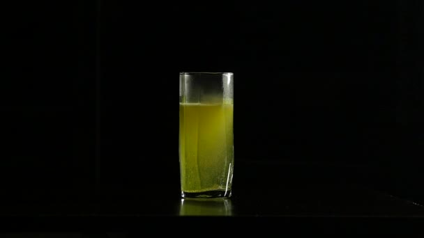 Γκρο πλαν αναβράζον δισκίο διαλύεται σε ένα ποτήρι νερό σε σκούρο φόντο, αργή κίνηση — Αρχείο Βίντεο