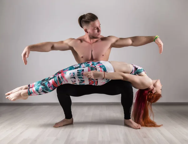 Sport muž a žena, která dělá acroyoga cvičení v temné místnosti — Stock fotografie