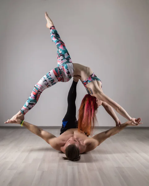 sports man and woman doing acroyoga exercises in a dark room