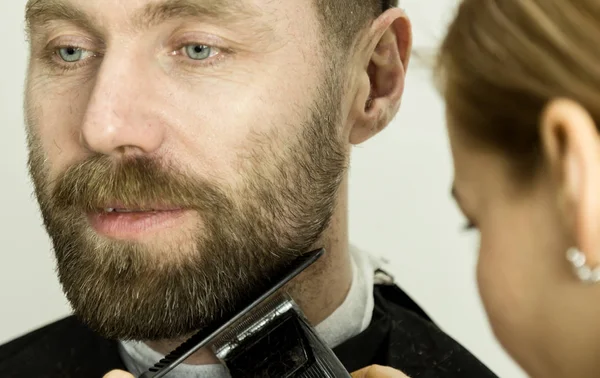 Парикмахерша ухаживает за бородой. Женщина парикмахер делает стрижку бороды взрослых мужчин — стоковое фото