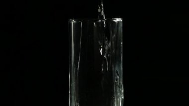 Karanlık bir arka plan ağır çekim cam içine su doldurma