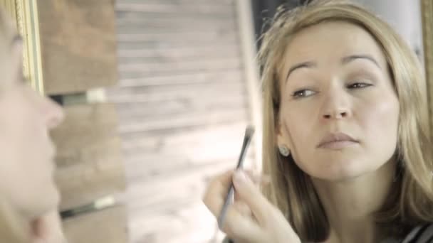 Femeia frumoasă face machiaj de zi cu zi și deține perie de machiaj în fața oglinzii — Videoclip de stoc