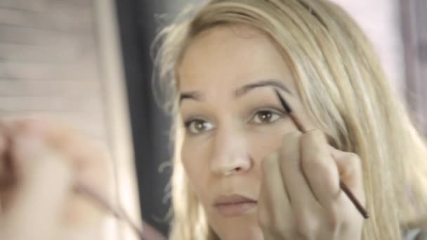 Красива жінка робить повсякденний макіяж і тримає пензлик перед дзеркалом — стокове відео