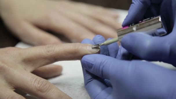 Mulheres mãos enquanto pintando suas unhas com polonês vermelho no salão de beleza — Vídeo de Stock