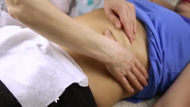 Женщина-врач делает пациенту массаж живота — стоковое видео