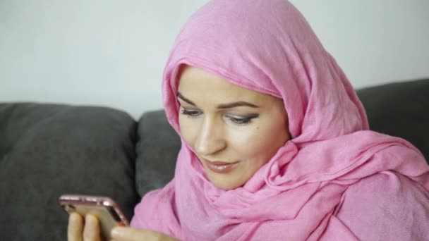 Jovem muçulmana está conversando com seus amigos. telefone celular nas mãos de uma mulher árabe vestindo um hijab — Vídeo de Stock