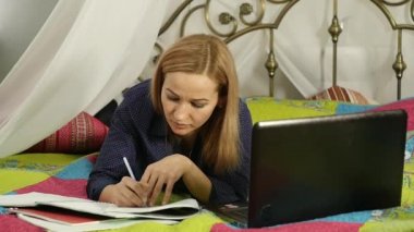 güzel kadın yatak odasında dizüstü bilgisayar ile eğitim. on-line eğitim