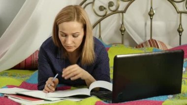 Öğrenci ev bir yatakta yatarken. onu laptop çalışan kadın. on-line eğitim. ağır çekim