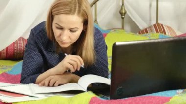 Öğrenci ev bir yatakta yatarken. onu laptop çalışan kadın. on-line eğitim
