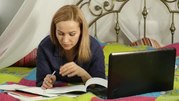 Estudiante acostado en una cama en casa. mujer trabajando en su portátil. educación en línea. cámara lenta — Vídeos de Stock