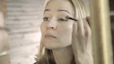 Güzel sarışın kadın her gün makyaj aynası, önünde küçük bir fırça ile kaşları çizer