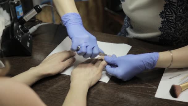 Manikyr putsning nagelband till kvinnans anlagda hand i nagelsalongen. processen att skära nagelbanden — Stockvideo