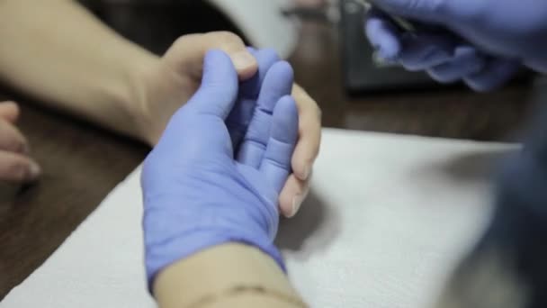 Manicurist trimming the cuticle to womans manicured hand in nail salon. process of cutting cuticle — Stock Video