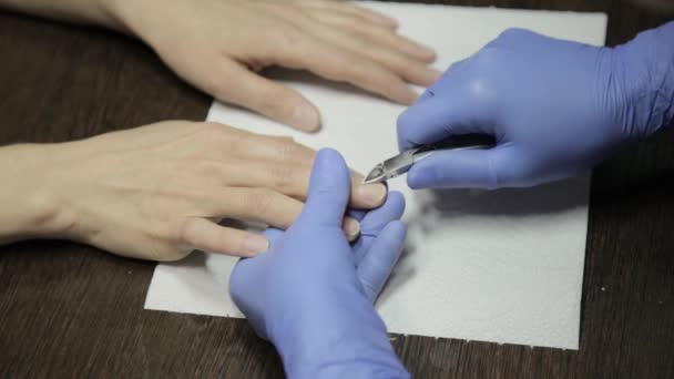 Manikyr putsning nagelband till kvinnans anlagda hand i nagelsalongen. processen att skära nagelbanden — Stockvideo