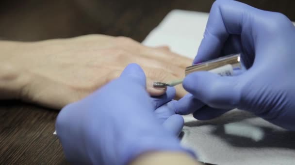 Dames handen tijdens het schilderen haar nagels met rode lak in de beauty salon — Stockvideo