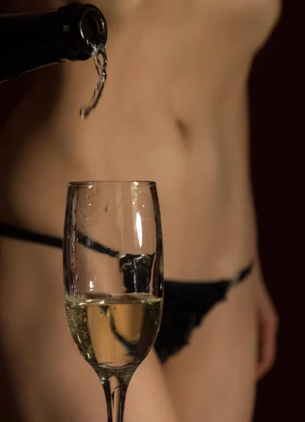 Sexy corpo mulher em roupa interior preta derrama champanhe em vidro — Fotografia de Stock