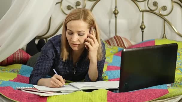 Student liggend op een bed in huis. vrouw die op haar laptop werkt. het online onderwijs. Slow motion — Stockvideo