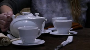 Kadın cafee beyaz bir bardak bitkisel çay dökülen. ağır çekim