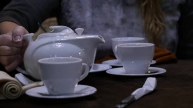 Kadın cafee beyaz bir kupa bitkisel çay dökülen. ağır çekim