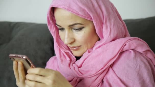 Jonge moslimvrouw is chatten met haar vrienden. mobiele telefoon in de handen van een Arabische vrouw het dragen van een hijab — Stockvideo