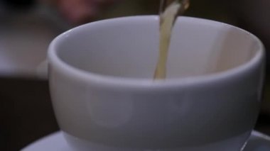 Yakın çekim çay cafee beyaz bardağa dökülür varlık. ağır çekim