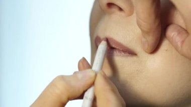 Profesyonel makyaj sanatçısı modeli dudaklarından kontur uygulamak. moda endüstrisi kozmetik