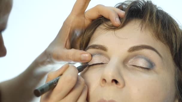 Nahaufnahme eines professionellen Visagisten, der Eyeliner auf das Augenlid aufträgt. Kosmetik in der Modebranche — Stockvideo