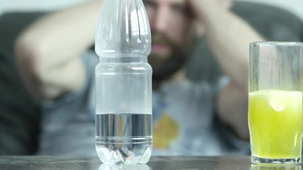 Крупним планом випромінювальна таблетка в склянці води, підкреслив депресивний суїцидний молодий чоловік. 4-кілометровий — стокове відео