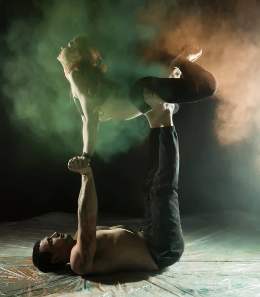 カラフルな煙と暗い部屋で acroyoga 演習を行う若いスポーツ カップル — ストック写真