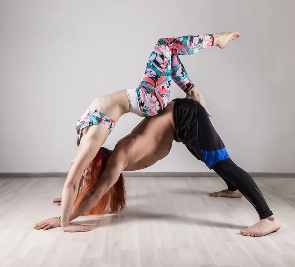 Sports man and woman doing acroyoga exercises in a dark room — Stock Photo, Image